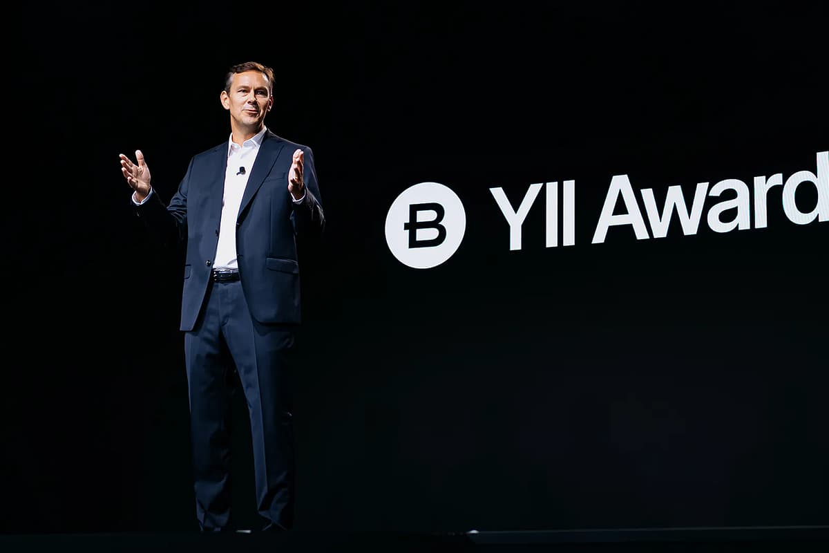 man in suit stands in front of screen that says Yii Awards