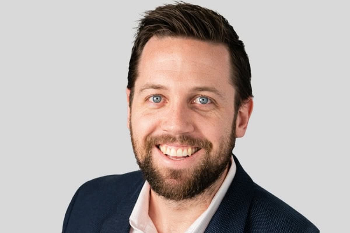 Man with black jacket and white shirt smiling