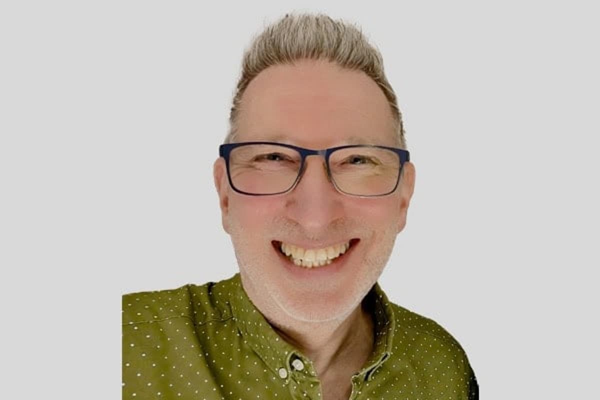 Man with green polka dot shirt and glasses, smiling