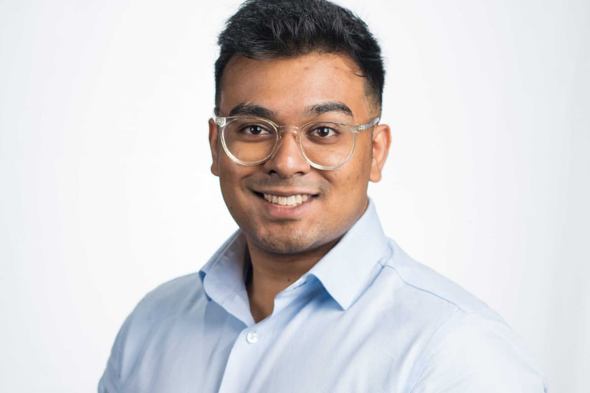 Man in blue shirt and wearing glasses, smiling