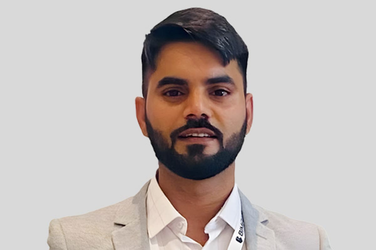 Man with beard, tan jacket and white shirt, smiling