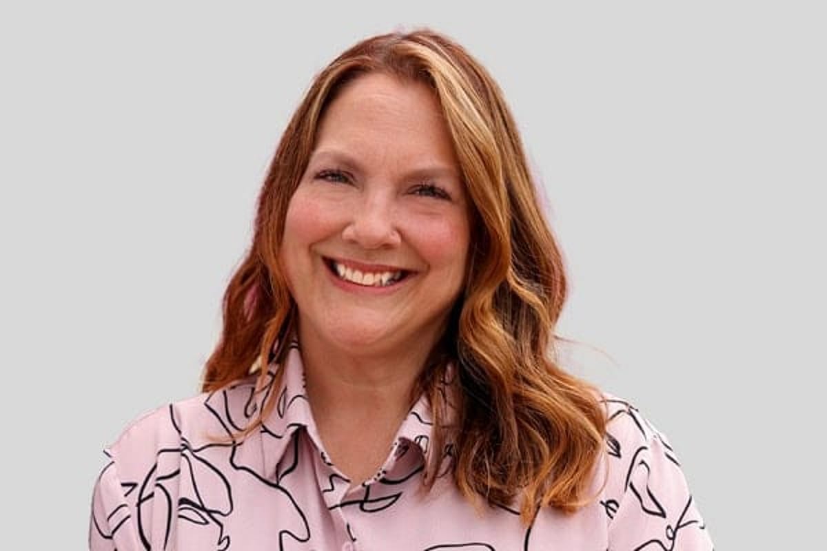 Woman with long hair and pink shirt, smiling