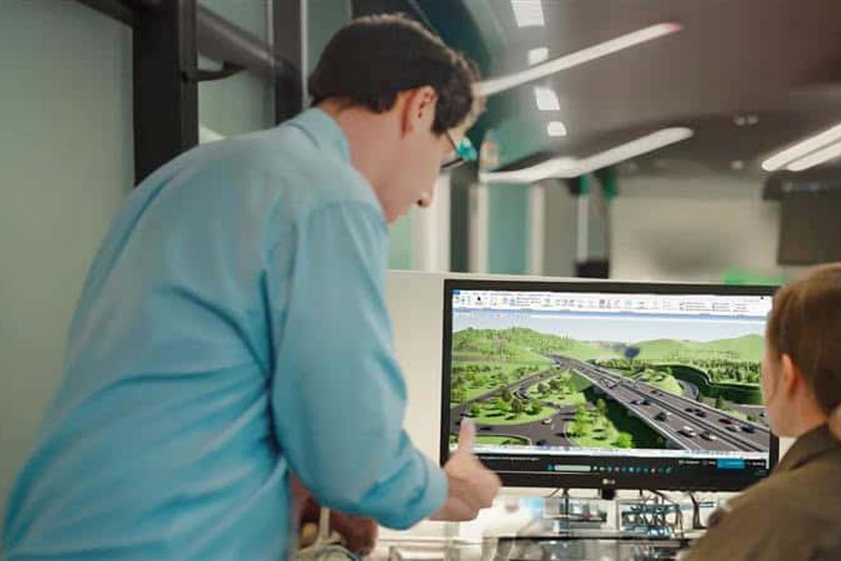 Man in blue explains concept to female student sitting in front of computer monitor