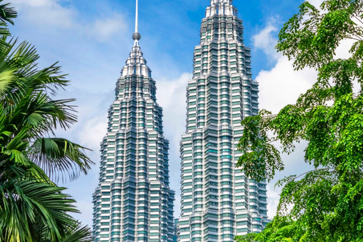 Two side-by-side buildings against sky backdrop with trees on each side