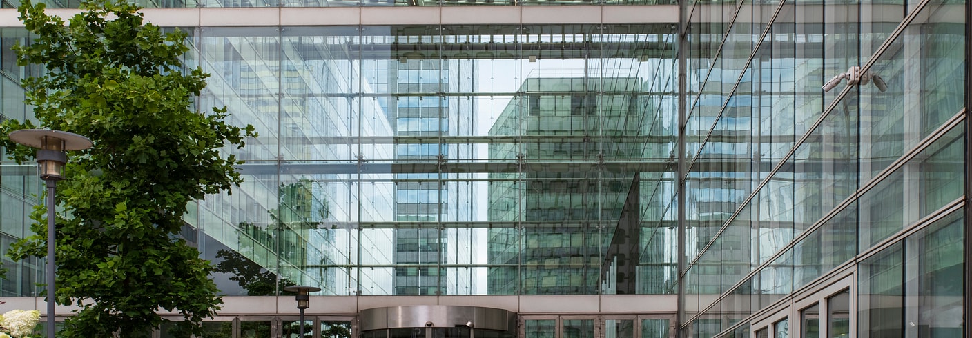 A glass building with multiple doors and a tree