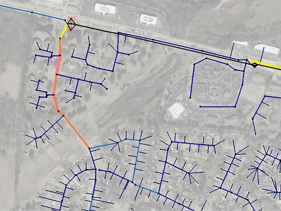 Municipal sewer network model in OpenFlows Sewer, displaying underground collection pipes color-coded by flow rate or pipe capacity along suburban roadways.
