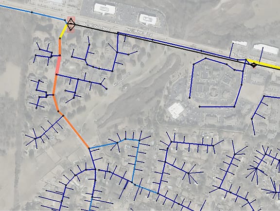 Municipal sewer network model in OpenFlows Sewer, displaying underground collection pipes color-coded by flow rate or pipe capacity along suburban roadways.