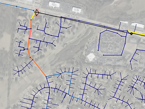 Municipal sewer network model in OpenFlows Sewer, displaying underground collection pipes color-coded by flow rate or pipe capacity along suburban roadways.