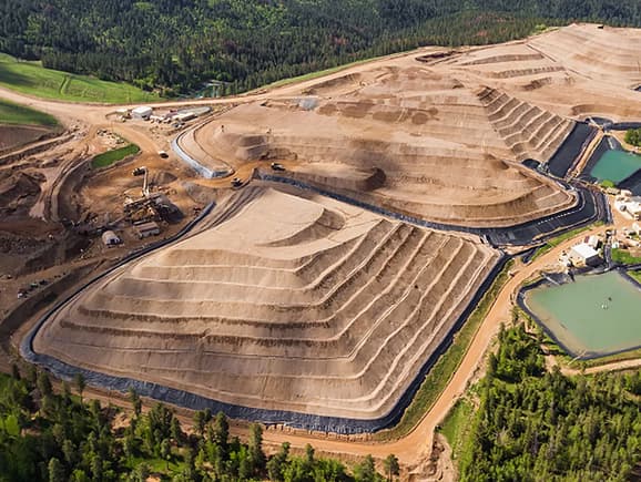 An aerial perspective of terraced mine earthworks and containment basins, illustrating safe waste management, environmental engineering, and sustainable above-ground mining operations.