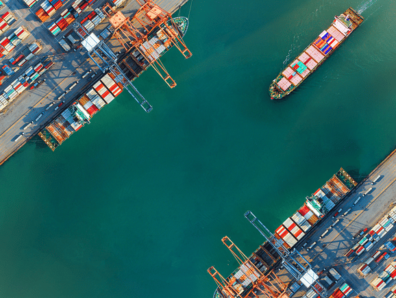 View of a bustling container terminal with cargo ships docked at berths and gantry cranes in operation, showcasing global trade via ports and waterways, marine supply chains, and efficient logistics infrastructure.