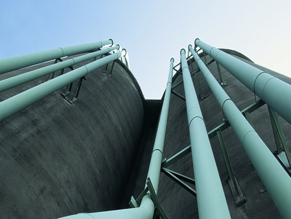 Low-angle perspective of large concrete storage silos with industrial piping, highlighting robust municipal water distribution and treatment infrastructure.