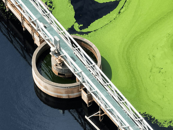 Aerial view of an active wastewater clarifier tank and service bridge, showcasing sustainable municipal sewage treatment and environmental water quality management.