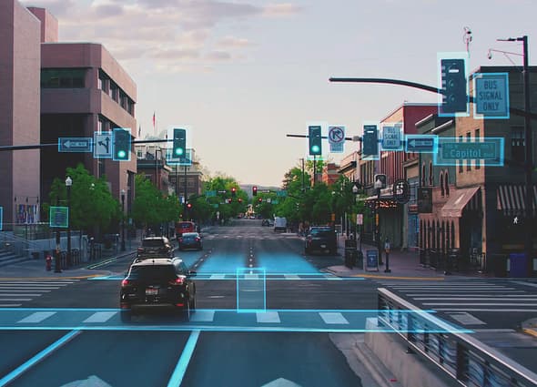 Blyncsy AI-powered computer vision view of an urban street, showing green bounding boxes detecting traffic signals, road lanes, crosswalks, and traffic signs in real-time.
