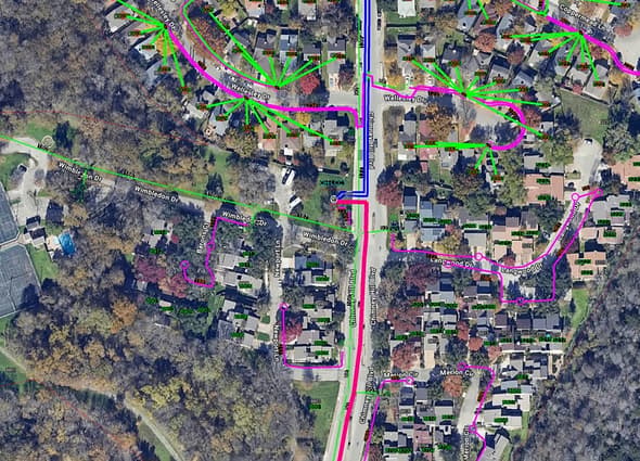 Detailed fiber-to-the-home network mapping in OpenComms Designer, showing color-coded coaxial lines connecting suburban properties to distribution hubs.