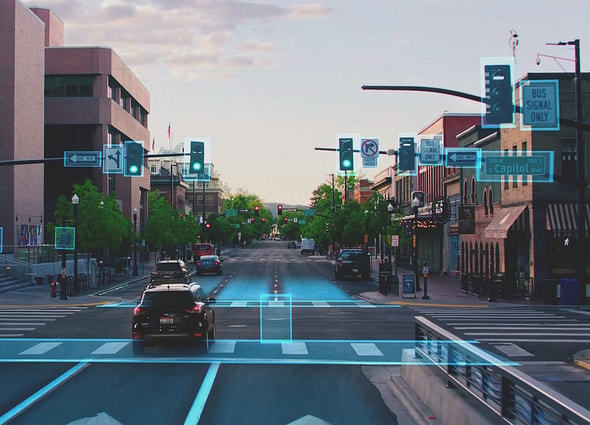 Blyncsy AI-powered computer vision view of an urban street, showing green bounding boxes detecting traffic signals, road lanes, crosswalks, and traffic signs in real-time.