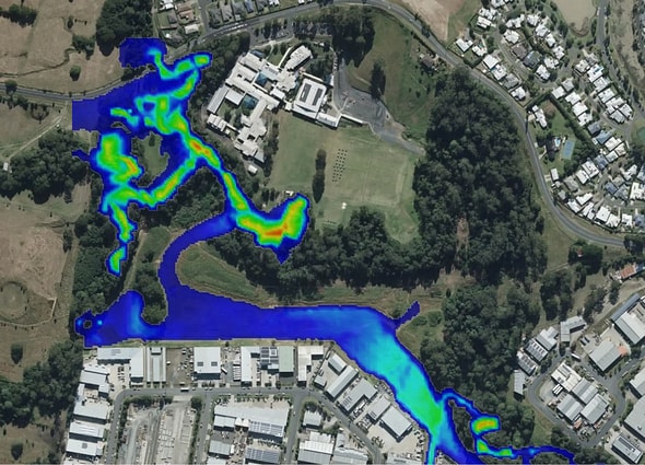 Top-down aerial view of a river channel in OpenFlows FLOOD showing a multi-colored heat map of water depth and flood inundation risk overlaying adjacent terrain.
