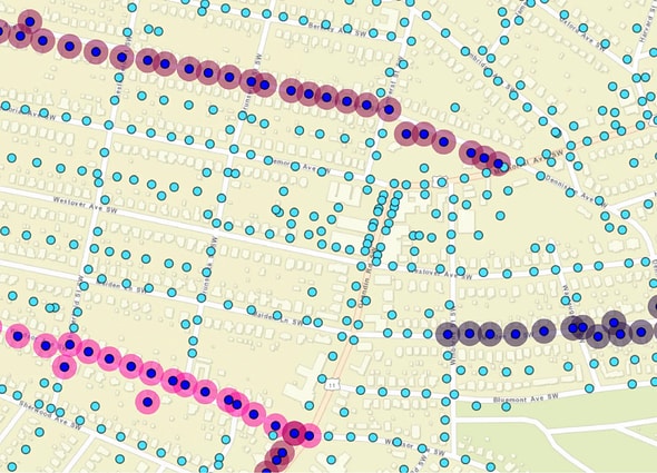 A GIS geographic map showing street grids of an urban area populated with blue, red, pink, and gray circular icons representing utility pole assets and lines in SPIDAstudio, demonstrating utility asset management.