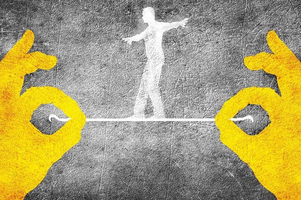 Yellow hands hold white string with figure of a human walking on it