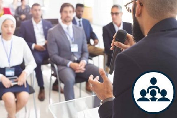 Man speaks to group of adults sitting in chairs