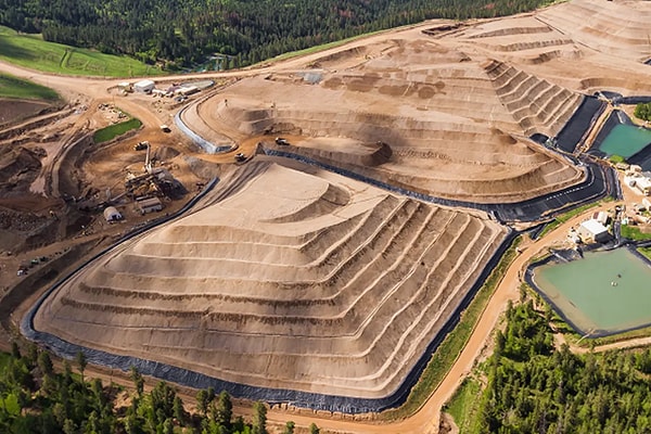 An aerial perspective of terraced mine earthworks and containment basins, illustrating safe waste management, environmental engineering, and sustainable above-ground mining operations.