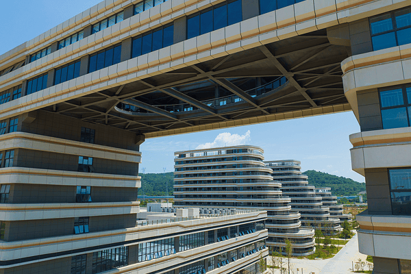 An eye-level view of a modern office complex connected by an elevated sky-bridge, highlighting innovative architectural engineering, collaborative spaces, and sustainable commercial design.