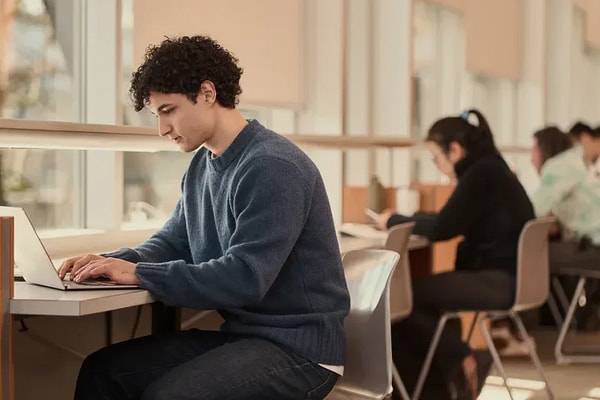 Students work on laptops at desks inside building