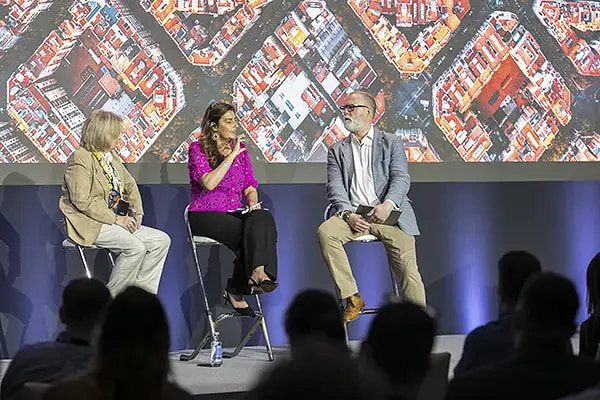 Conference participants sitting on a stage speaking into microphones