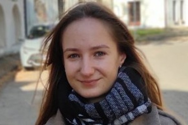 Woman with long hair and scarf, smiling outdoors