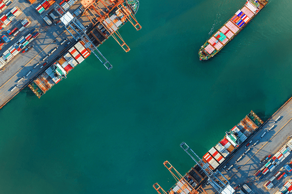 View of a bustling container terminal with cargo ships docked at berths and gantry cranes in operation, showcasing global trade via ports and waterways, marine supply chains, and efficient logistics infrastructure.