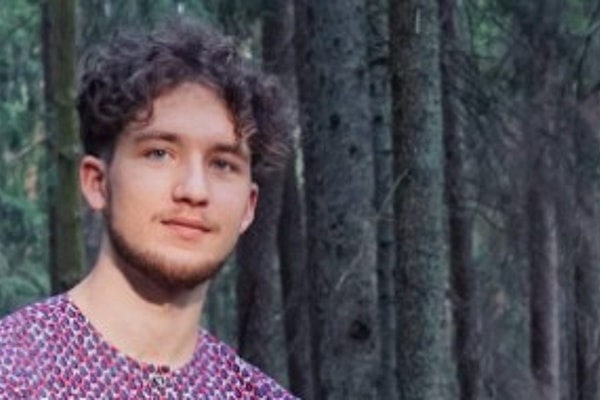 Man in purple shirt smiling slightly