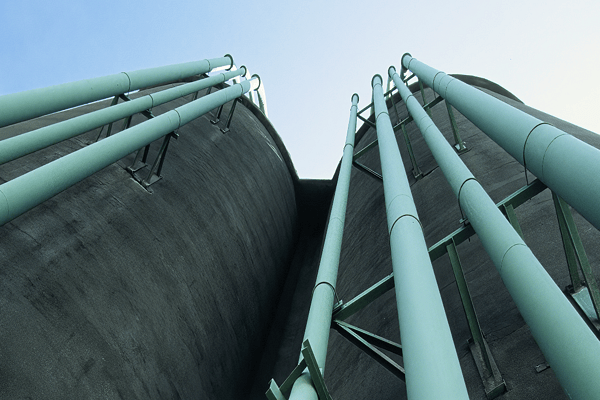 Low-angle perspective of large concrete storage silos with industrial piping, highlighting robust municipal water distribution and treatment infrastructure.