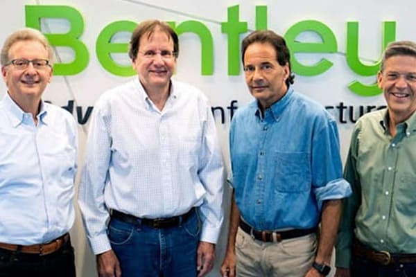 Four men in business attire smile for group photo