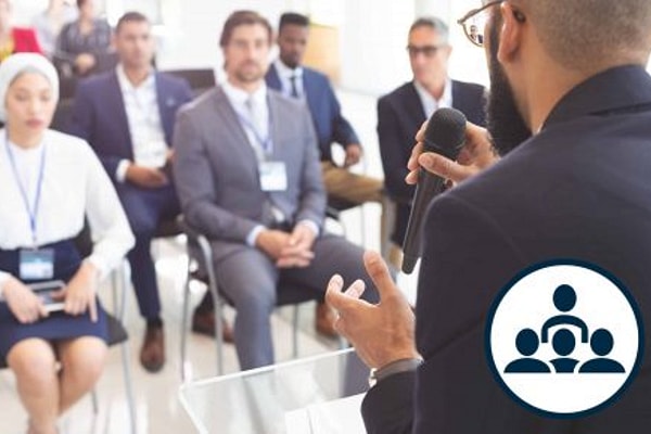 Man speaks to group of adults sitting in chairs