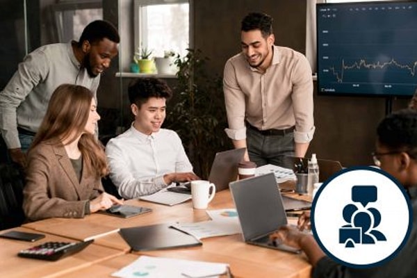 Group of adults sit and stand around a conference room table