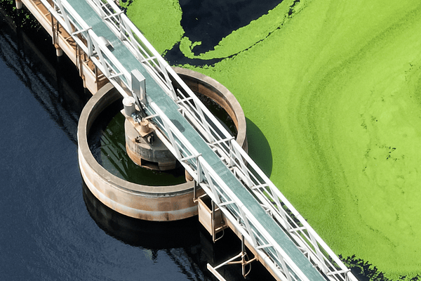 Aerial view of an active wastewater clarifier tank and service bridge, showcasing sustainable municipal sewage treatment and environmental water quality management.
