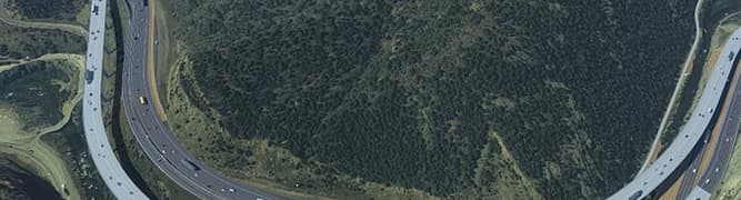 A 3D digital model of the I-70 Floyd Hill project in Colorado, showing the redesigned highway with new viaducts curving through the steep mountain terrain.