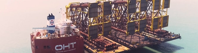 An aerial view of the five wellhead platform jackets, designed by Sapura Energy using SACS software, being transported from the fabrication yard on a heavy lift vessel.