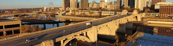 Aerial view of vehicles crossing the Robert Street Bridge, set against a backdrop of skyscrapers under a clear blue sky in St. Paul, Minnesota.