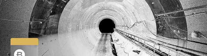 Black and white image showing the interior of a large, circular tunnel with cables running along the right side—an impressive project by Italferr S.p.A.; a gray badge at left reads “B Winner 2025.”