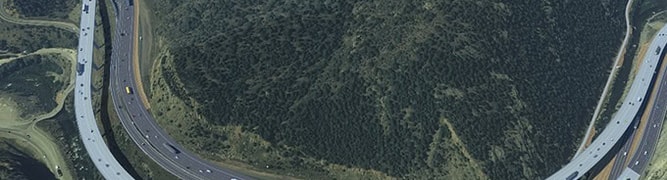  A 3D digital model of the I-70 Floyd Hill project in Colorado, showing the redesigned highway with new viaducts curving through the steep mountain terrain.