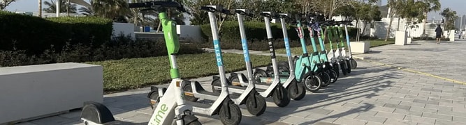 A row of shared e-scooters parked on a sidewalk in Abu Dhabi, representing the micromobility network that the Integrated Transport Centre regulates using a digital twin.