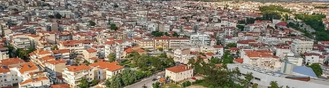 Aerial view of the city of Kozani, Greece, nestled in a valley with mountains in the background