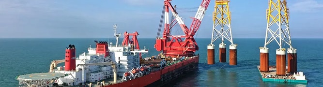A heavy-lift vessel installing large foundations for an offshore wind farm in the open sea 