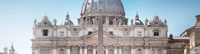 St. Peter's Basilica with a central obelisk in St. Peter's Square, Vatican City, under a clear blue sky.
