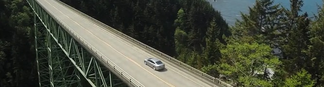 A long bridge spanning a forested coastline in Oregon, representing one of the thousands of assets that ODOT now manages in a unified system.