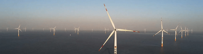 Aerial view of a large offshore wind farm with many turbines in the open sea 