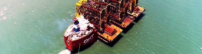 An aerial view of the OHT Albatross carrying three 8,000-metric-ton wellhead platform jackets, a strategy that cut transport costs by 40% for Vantris Energy.