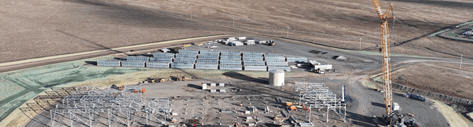 The construction site for Fervo Energy's Cape Station, the world's largest next-generation geothermal project, with a crane and the structural steel for the power plant in the foreground and mountains in the background.