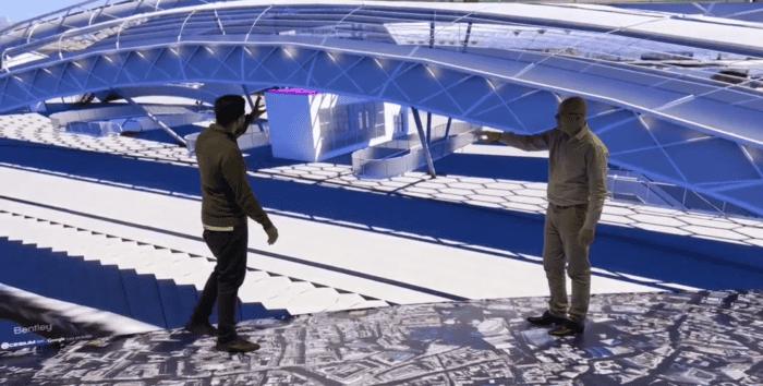 Engineers review a detailed 3D model of a modern architectural structure displayed above them.