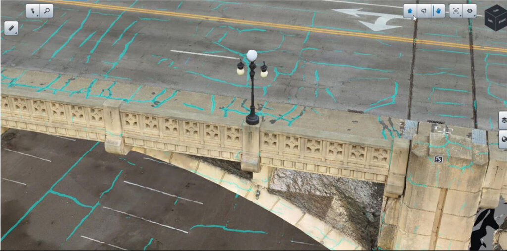 Aerial view of a streetlamp on a concrete bridge over a parking lot, with blue survey lines marked on the bridge and road, captures the precision of Unified Reality Modeling in creating Intelligent Digital Twins for urban infrastructure.